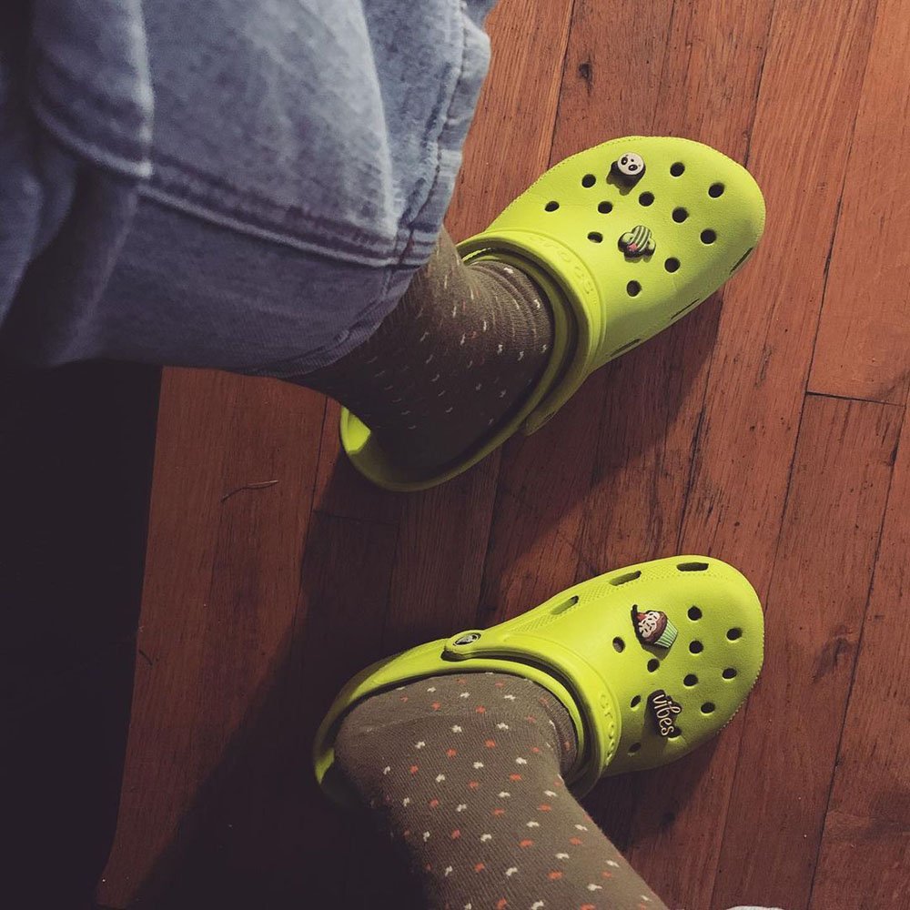Feet shown wearing lime punch Crocs Classic Clogs with black socks