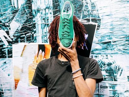 Lil Tecca playfully holding a green PUMA Suede sneaker in front of his face